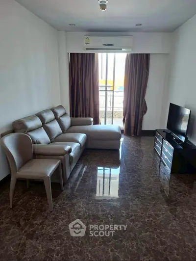 Spacious living room with modern sofa and TV, featuring elegant marble flooring and natural light.