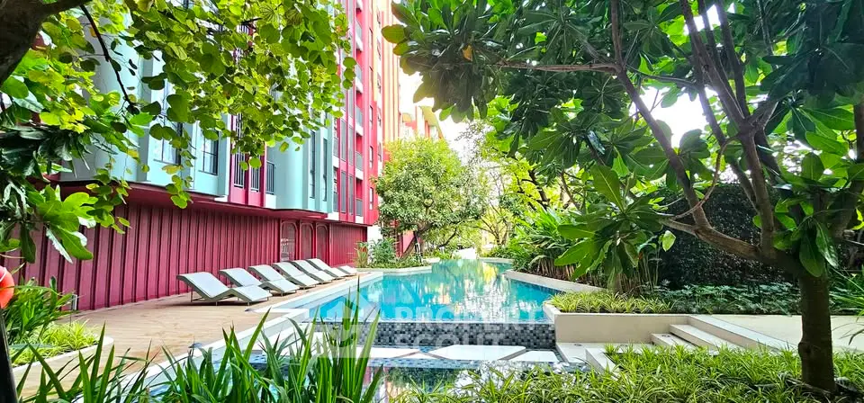 Luxurious poolside view with lush greenery and modern building facade, perfect for relaxation and leisure.
