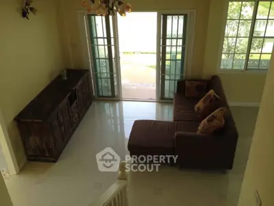 Spacious living room with elegant sofa and large windows opening to a garden view.