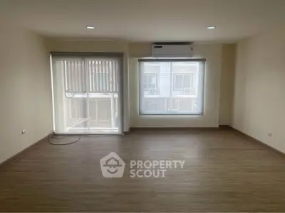 Spacious unfurnished room with large windows and wooden flooring, ideal for customization.