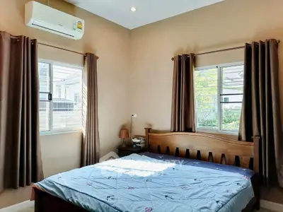 Cozy bedroom with natural light, featuring a wooden bed and air conditioning, perfect for relaxation.