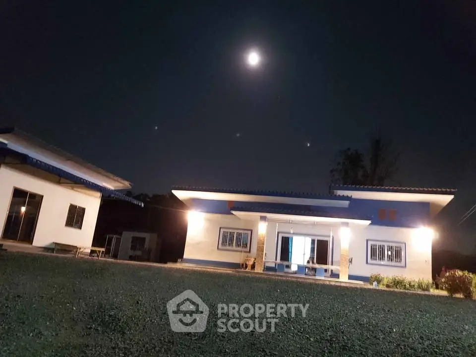 Charming night view of a modern single-story home with moonlit ambiance and spacious lawn.