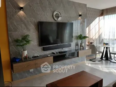 Modern living room with wall-mounted TV, sleek furniture, and large windows for natural light.