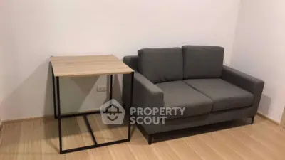 Modern minimalist living room with sleek gray sofa and stylish wooden side table.