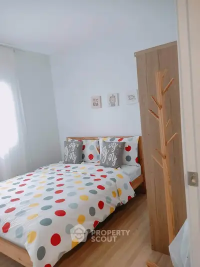Charming bedroom with colorful polka dot bedding and wooden furniture, perfect for cozy living.