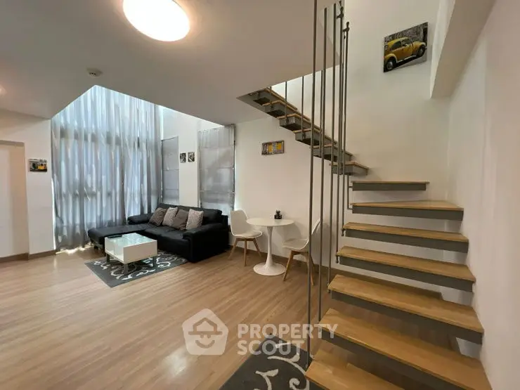 Modern duplex living room with stylish staircase and cozy seating area.