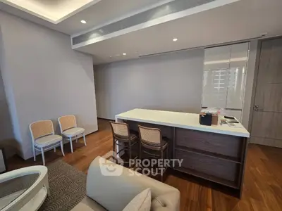 Modern living room with sleek design and wooden flooring, featuring a stylish kitchen island and cozy seating area.