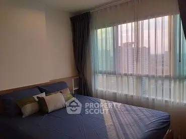 Cozy bedroom with large window offering city view, featuring stylish bedding and elegant curtains.