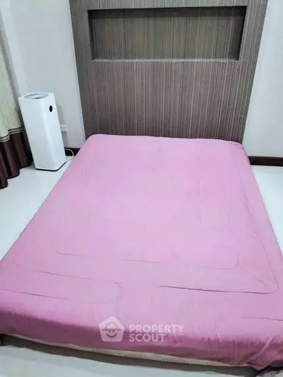 Cozy bedroom with pink bedding and modern air purifier, perfect for restful nights.