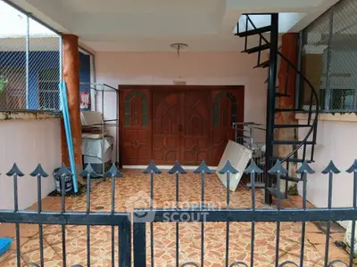 Charming entrance with spiral staircase and decorative gate in a cozy residential property.