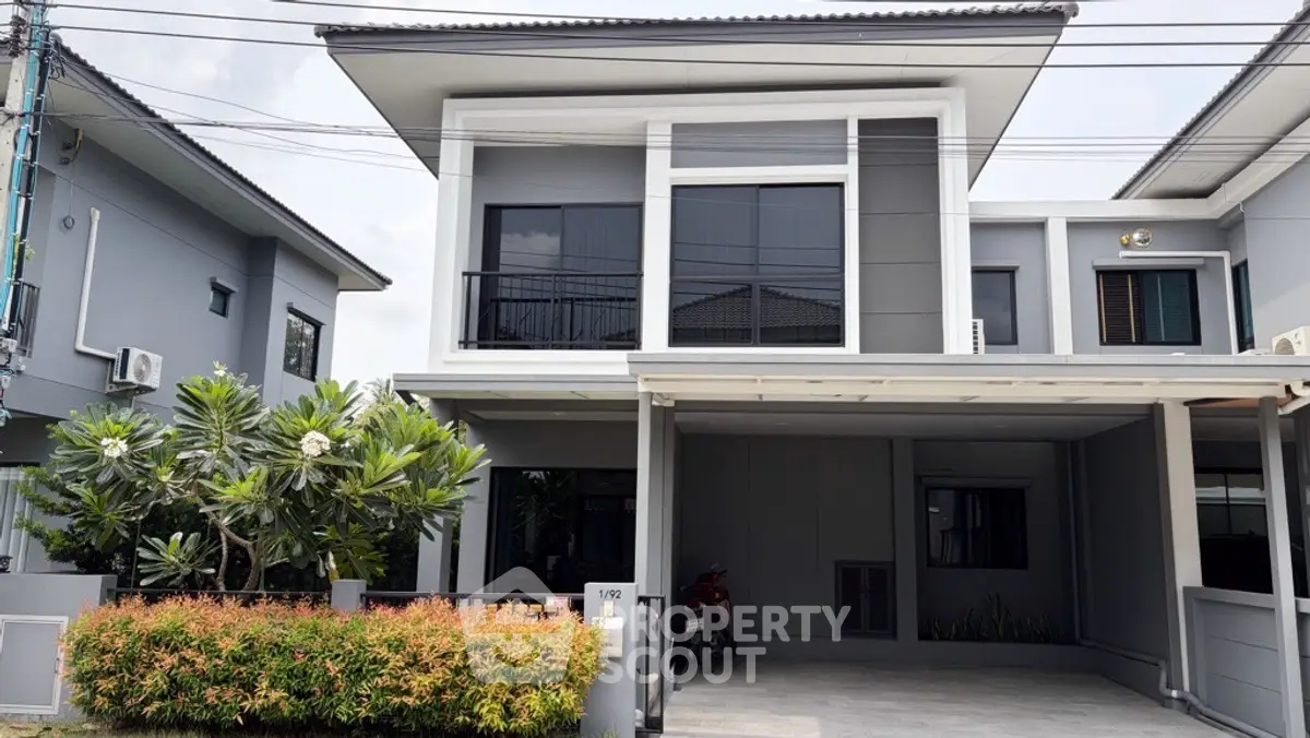 Modern two-story house with sleek design and spacious carport in a suburban neighborhood.