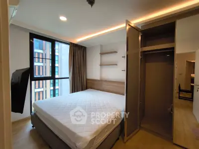 Modern bedroom with large window and built-in wardrobe in a stylish apartment.