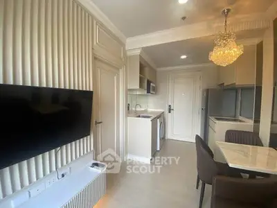 Modern apartment interior with elegant kitchen and dining area, featuring a chandelier and wall-mounted TV.