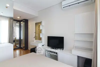 Modern bedroom with sleek furniture and wall-mounted TV in a stylish apartment.
