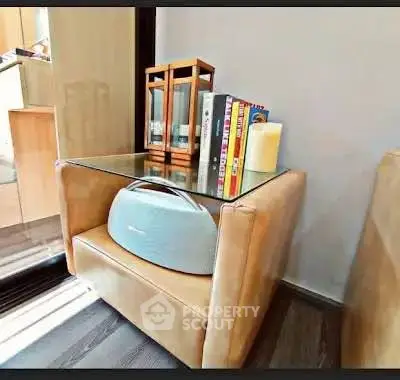 Stylish modern living room corner with glass-top side table and books, perfect for cozy reading.