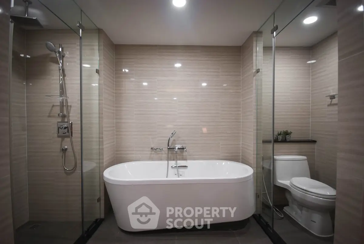 Luxurious modern bathroom with freestanding bathtub and glass shower enclosure.