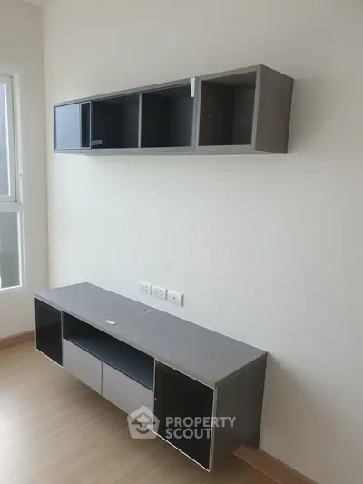 Modern minimalist living room with sleek wall-mounted storage units and natural light.