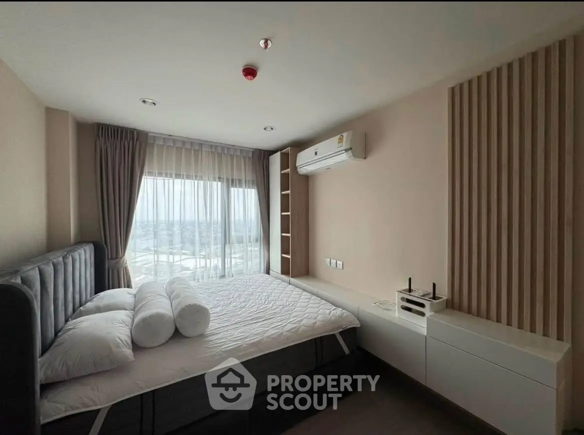 Modern bedroom with large window and stylish decor in a high-rise apartment.