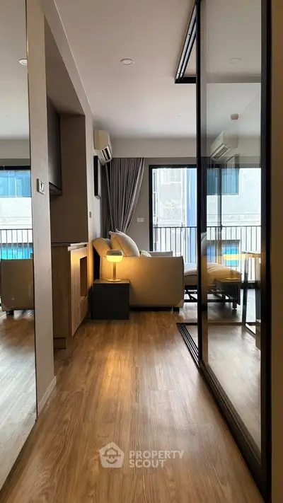 Modern living room with wooden flooring and large windows in a stylish apartment.