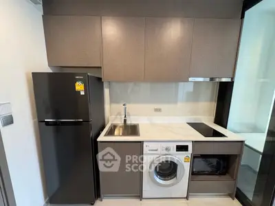 Modern kitchen with sleek appliances including fridge, washing machine, and induction cooktop.
