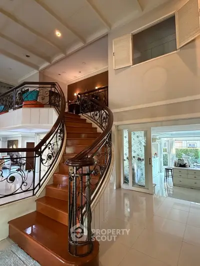 Elegant interior with grand staircase and open living area, showcasing luxury and spaciousness.