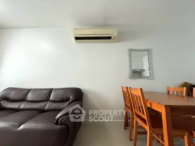 Modern living room with leather sofa, dining table, and wall-mounted air conditioner.