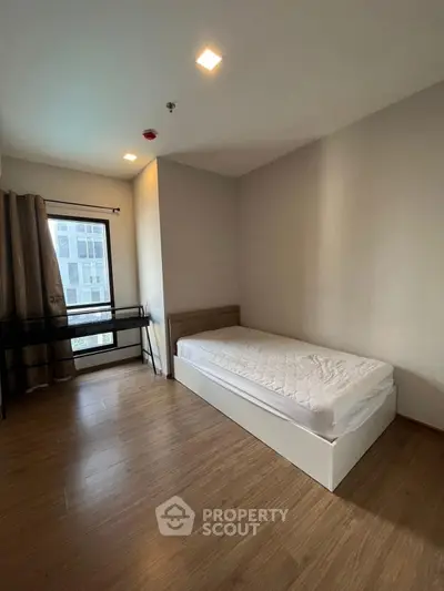 Spacious bedroom with single bed and large window in modern apartment