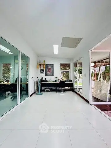 Spacious modern office space with glass partitions and outdoor view, ideal for productivity.
