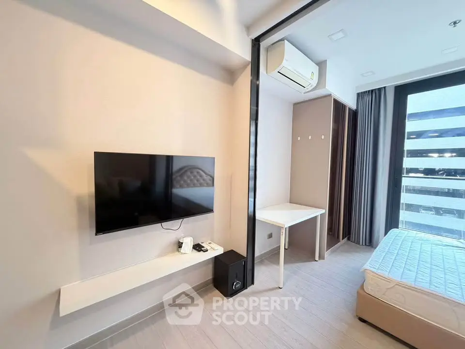 Modern bedroom with wall-mounted TV, air conditioning, and large window for natural light.