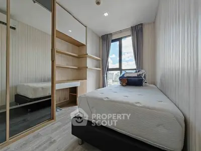 Modern bedroom with large window and built-in storage in a stylish apartment.
