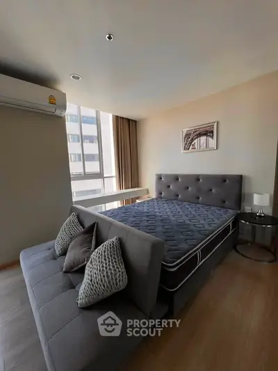 Modern bedroom with stylish decor and large window offering natural light