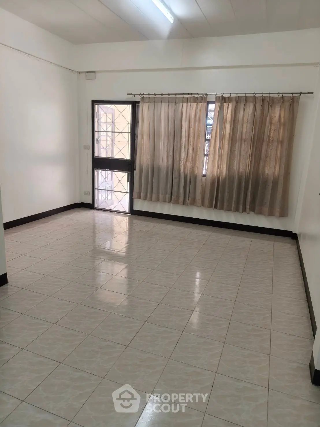 Spacious empty room with tiled flooring and large window, perfect for customization.