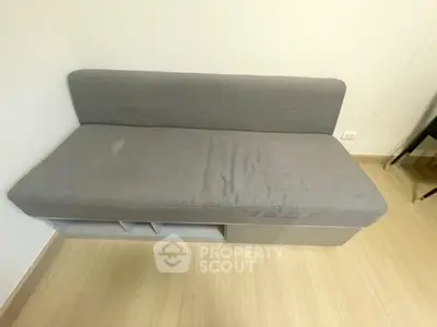 Compact gray sofa bed in minimalist living room with wooden flooring