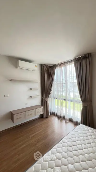 Spacious bedroom with large window and modern air conditioning unit