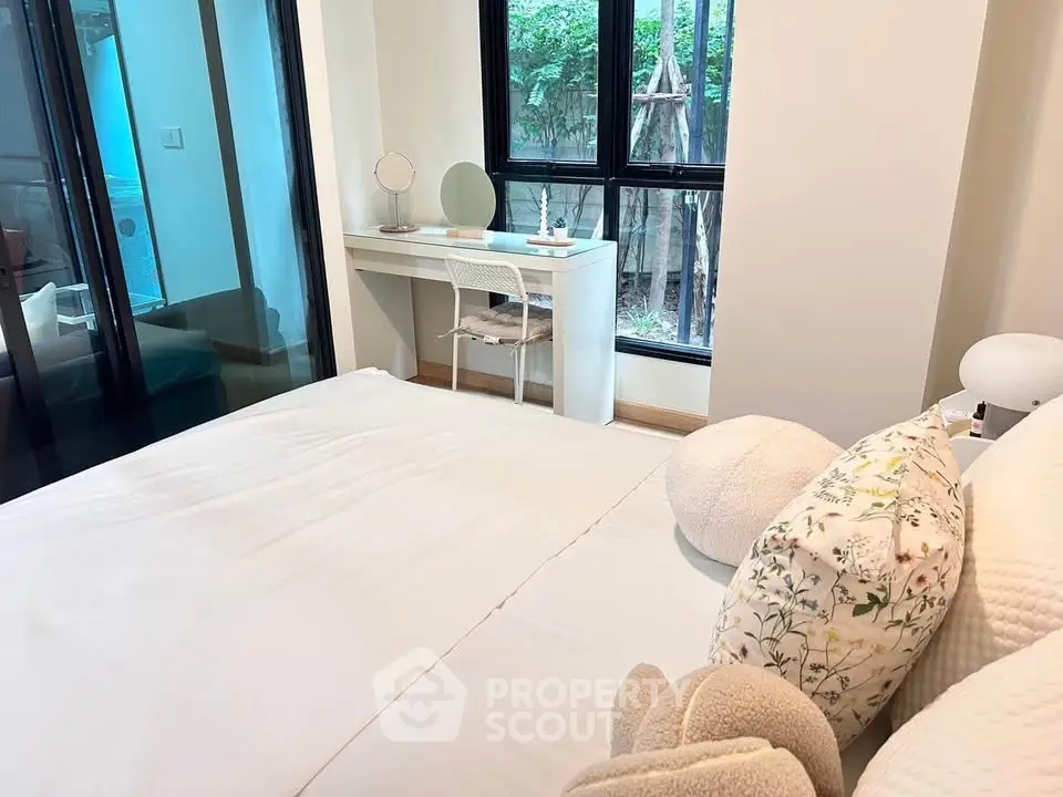Cozy bedroom with large windows and elegant decor, featuring a stylish vanity desk.