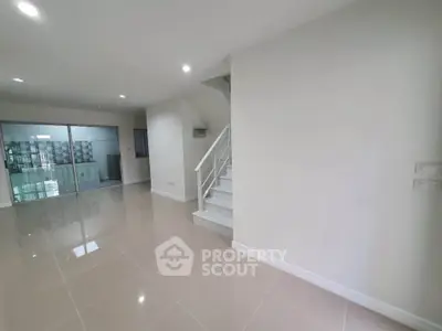 Spacious modern living room with glossy tile flooring and staircase