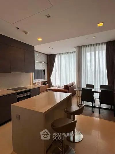 Modern open-layout kitchen and living room with stylish furniture and large windows.