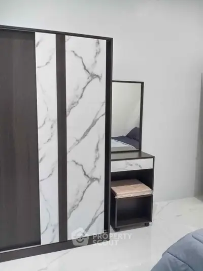 Modern bedroom with stylish wardrobe and sleek vanity set on marble flooring.