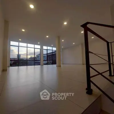 Spacious modern interior with large windows and sunset view, ideal for versatile living or office space.