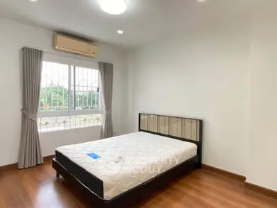 Spacious bedroom with large window and air conditioning in modern apartment.