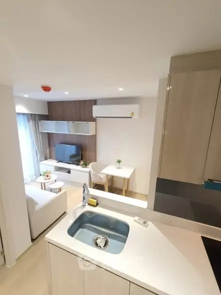 Modern open-plan living room with kitchen, featuring sleek design and natural light.