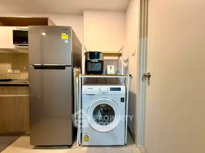 Modern kitchen with stainless steel fridge and washing machine in compact layout.
