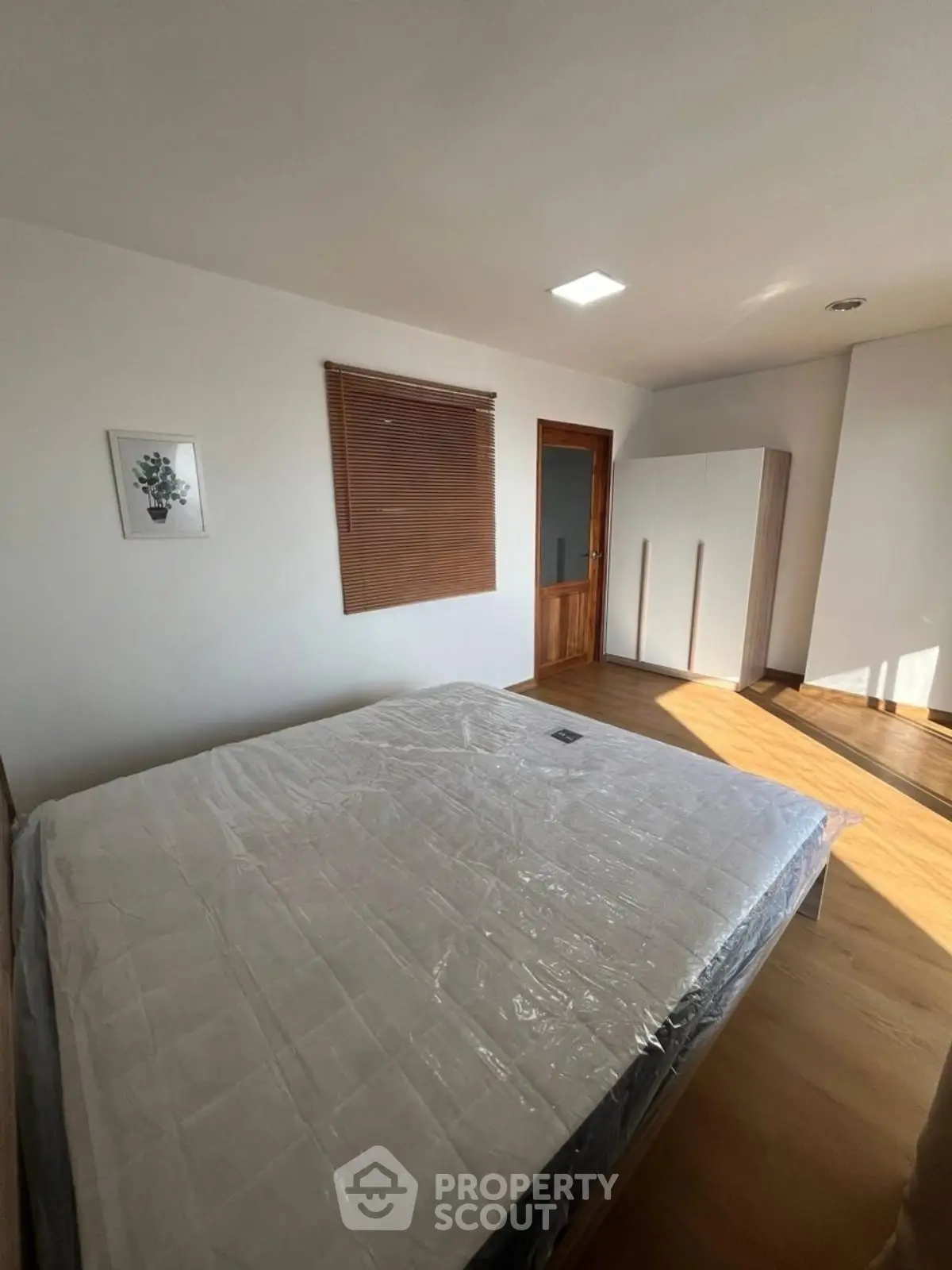 Spacious bedroom with natural light and modern wooden flooring