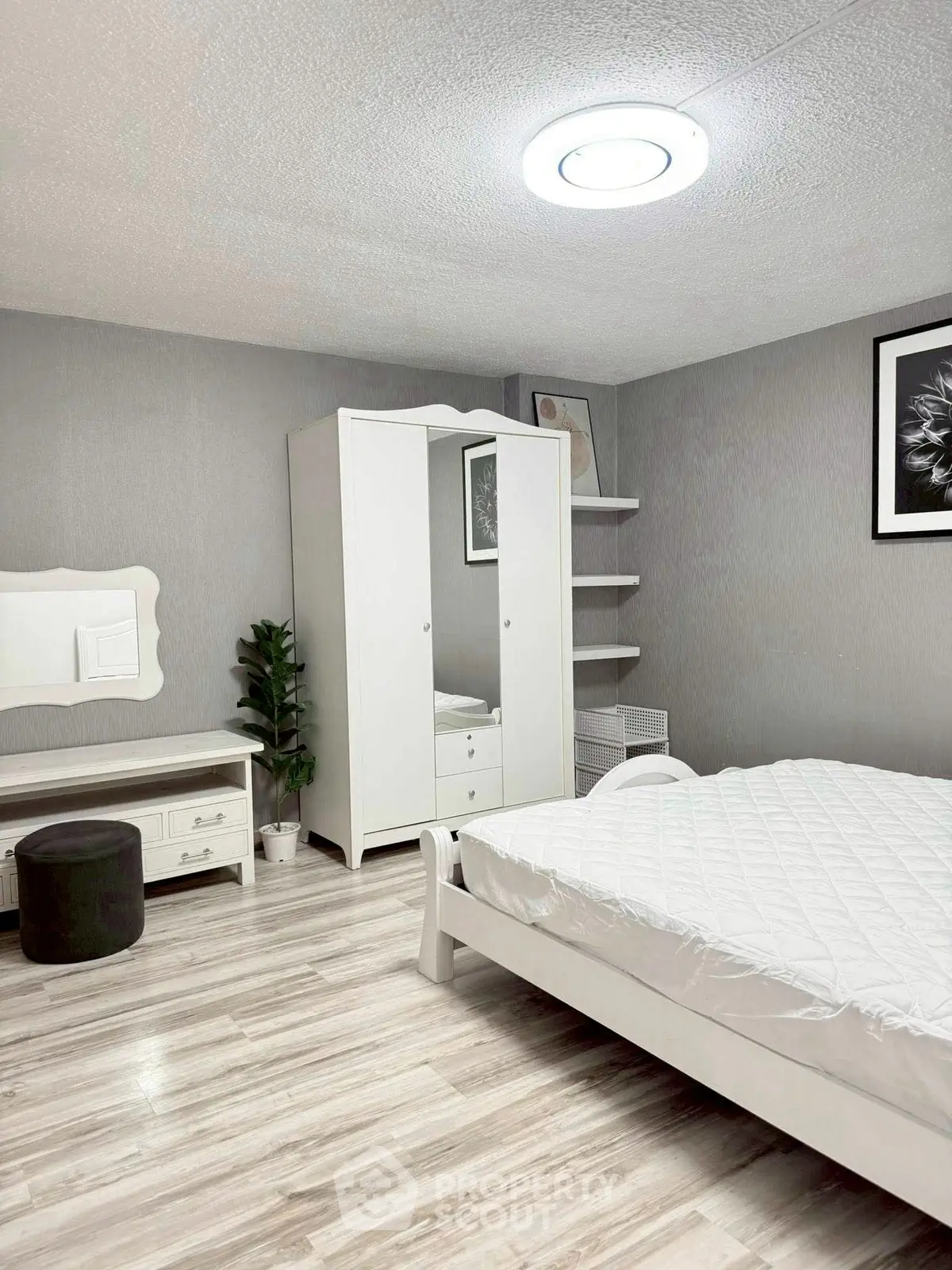 Spacious modern bedroom with elegant white furniture and stylish decor.