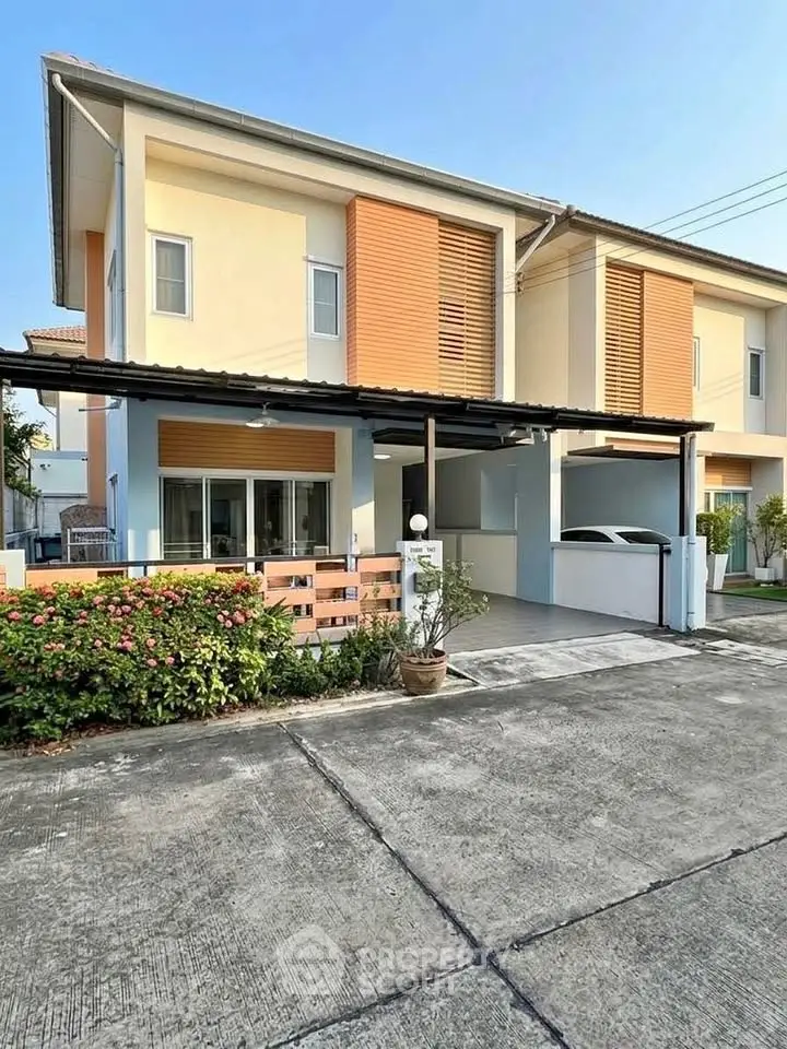 Modern two-story house with carport and landscaped front yard in a suburban neighborhood.