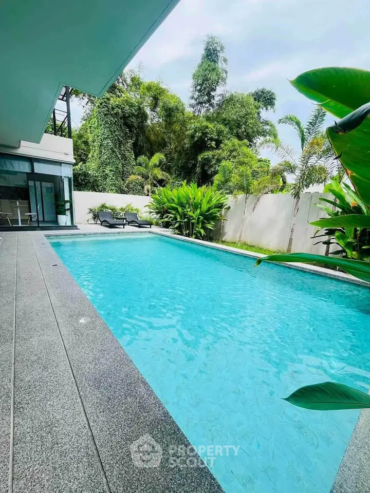 Luxurious modern home with a stunning private pool surrounded by lush greenery, perfect for relaxation and entertainment.