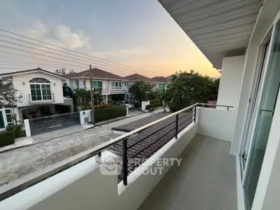 Charming balcony with serene neighborhood view at sunset, perfect for relaxation.