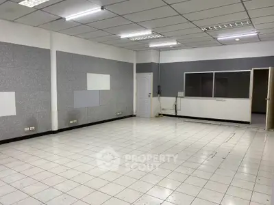 Spacious empty room with tiled flooring and fluorescent lighting, ideal for office or studio setup.