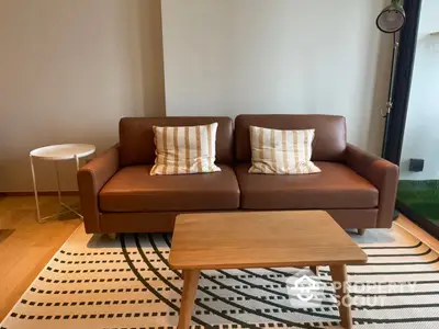 Chic modern living room with stylish brown leather sofa, patterned rug, and minimalist decor, perfect for urban living.