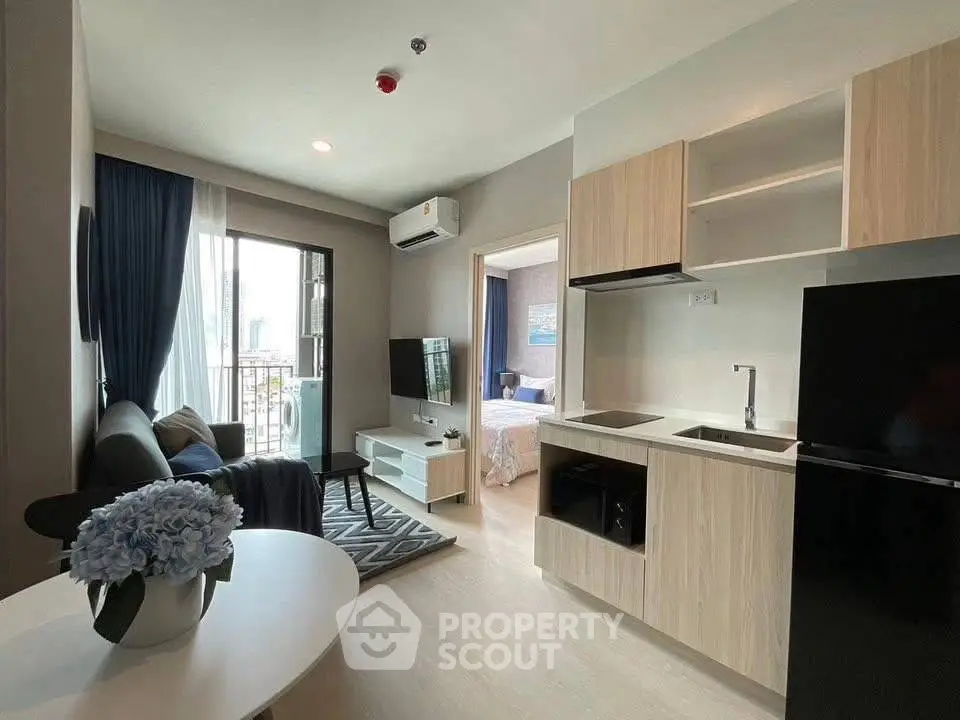 Modern open-plan living room with sleek kitchen and cozy bedroom view.